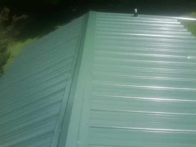 New green metal panels meeting at the ridge of a roof — Flat Roof Repair work by our crew in Killbuck