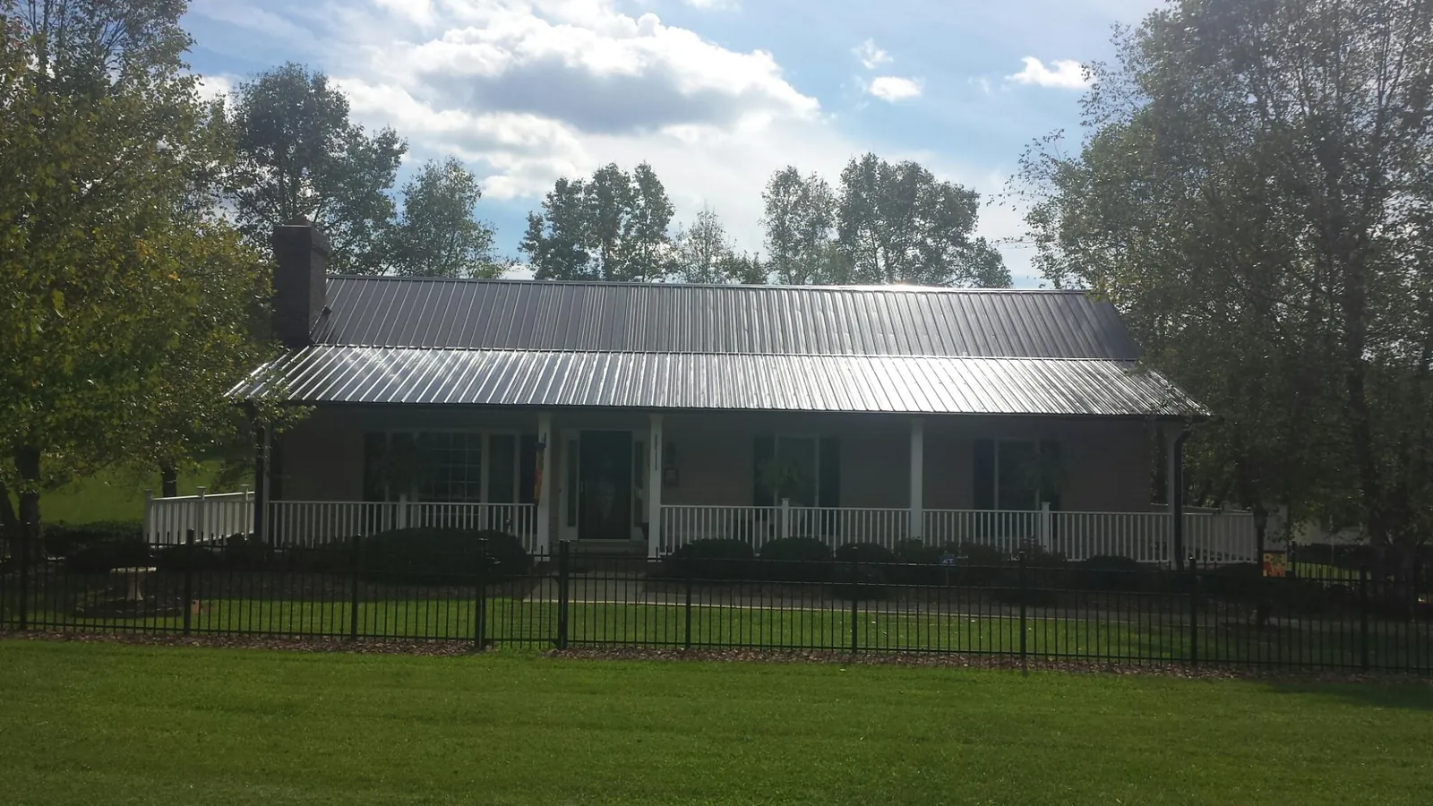 Gray metal roof on a brick ranch with a full width front porch — Gutter Guard Installation work by our crew in Killbuck
