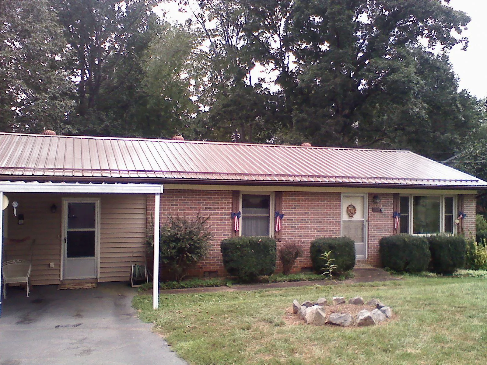 Bronze metal roof and carport on a brick ranch home — Roof Repair work by our crew in Killbuck