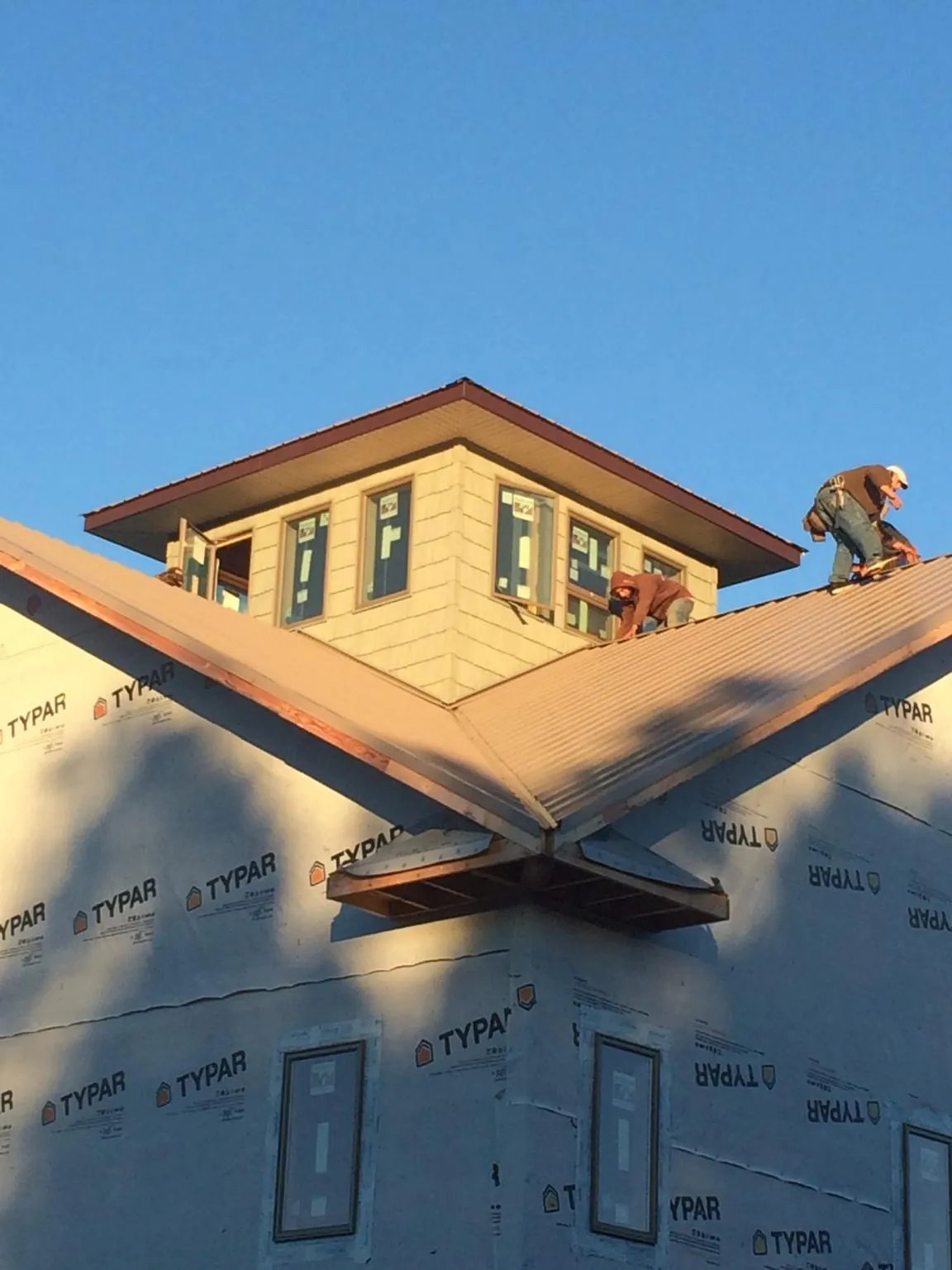 Roofers working around a rooftop cupola on a new metal roof at sunset — Roof Waterproofing in Killbuck by Roofing Brothers